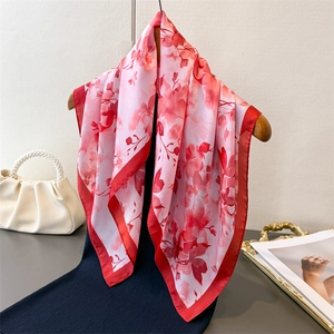 Élégant carré de soie rose avec imprimé floral rouge suspendu sur un cintre en bois