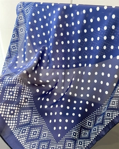 Détail d'un foulard en soie bleu marine à pois montrant la texture et le motif géométrique