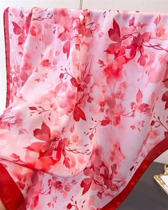 Gros plan du foulard en satin rose avec imprimé floral rouge et bordures de haute qualité