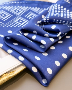 Détail d'un foulard en satin bleu roi à pois blancs avec une texture de soie élégante