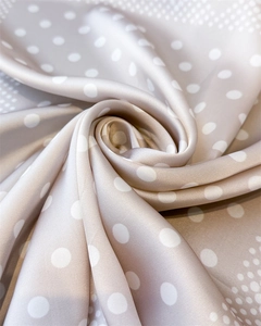 Gros plan d'un foulard en satin champagne plié en rose montrant la texture de la soie