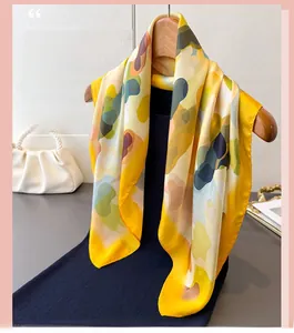 Detail of a bright yellow printed silk scarf draped on a wooden hanger with smooth texture