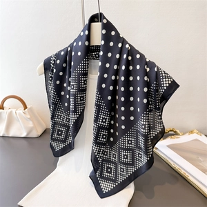 Élégant foulard en soie noir et blanc à motifs géométriques et pois sur un pull blanc