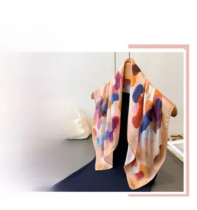 Detail of a large square scarf with vibrant abstract prints in orange and purple tones