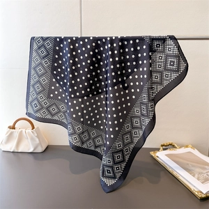 Détail d'un foulard en soie bleu marine avec pois blancs et motifs géométriques en losange