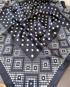 Détail d'un foulard en soie noir et blanc montrant les bords roulés et les motifs à pois
