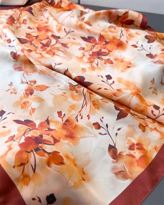 Détail d'un foulard en soie avec motif floral orange et couture de bordure fine