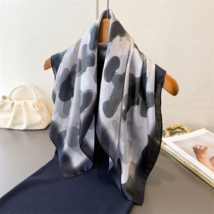 Close-up of artistic silk scarf with abstract monochrome pattern on a wooden hanger