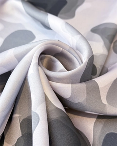 Macro shot of grey camouflage silk scarf fabric showing soft texture and glossy finish