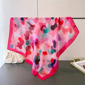Detail view of colorful abstract silk scarf draped over metal rod with smooth satin texture