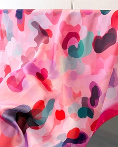 Close-up of pink printed silk scarf showing luxurious texture and artistic floral patterns