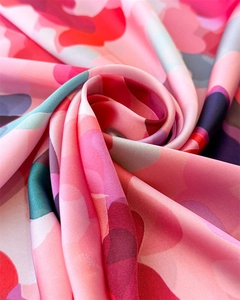 Close-up of pink abstract print silk scarf showing soft satin luster and smooth texture