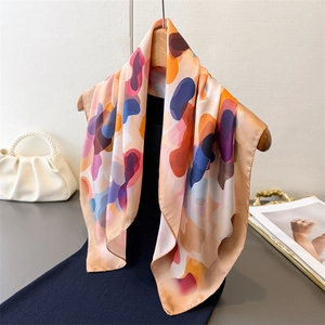 Elegant summer silk scarf with abstract colorful prints displayed on a wooden hanger