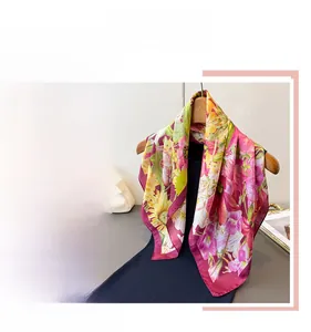 Detail of vibrant floral silk scarf with colorful botanical print and dark red rolled edges