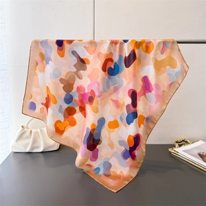 Detail of artistic floral pattern silk scarf draped over a gold rack with elegant accessories