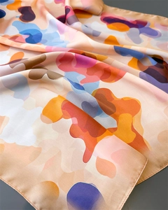 Detail of colorful abstract print silk scarf showing smooth texture and fine rolled edges