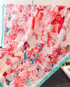 Detail of silk-like scarf featuring red floral butterfly print and cyan-blue hem