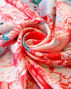 Macro detail of silk-like satin fabric with vibrant floral print and smooth texture