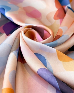 Detailed macro view of vibrant abstract print silk scarf with smooth satin luster texture