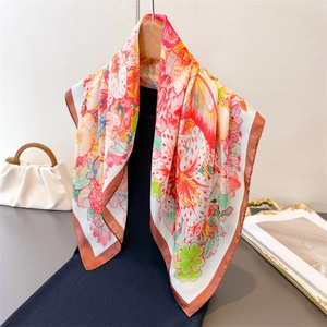 Elegant butterfly and flower print silk scarf draped on a wooden hanger with smooth texture