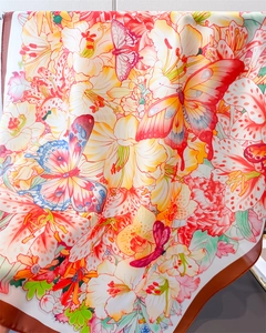 Detailed view of floral and butterfly print on silk-like satin square scarf with brown edges