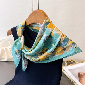 Detailed view of floral silk scarf with mint green and yellow patterns on a hanger
