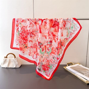 Close-up of elegant floral and butterfly silk scarf draped gracefully on a metal rod
