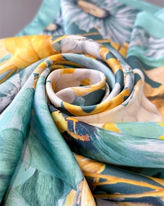 Close-up of floral silk scarf folded in rose shape showing green and yellow daisy patterns