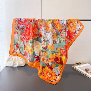 Detail of silk-textured square scarf featuring vibrant orange borders and floral patterns