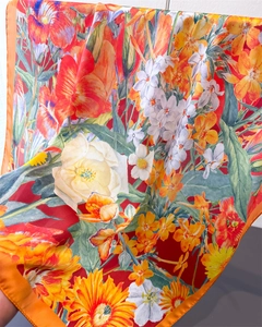 Detail of vibrant orange floral silk scarf featuring sunflower and lily print textures
