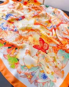 Close-up of orange butterfly silk scarf showing smooth texture and vibrant floral print