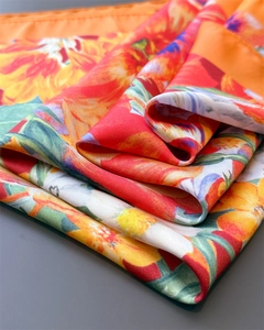 Detailed view of silky vintage square scarf with vibrant orange and red floral patterns