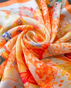 Close-up of floral print silk scarf showing smooth texture and warm orange floral pattern