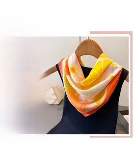 Détail d'un foulard carré en soie avec motifs de citrons et de fleurs blanches vives