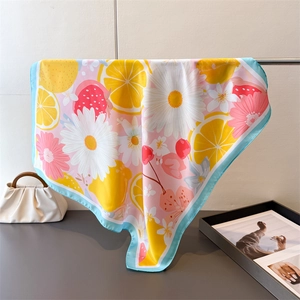 Détail d'un foulard en soie à imprimé floral et citron drapé sur un sac à main