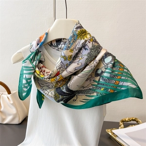 Detail of silk-like square scarf featuring tropical flora and fauna illustrations
