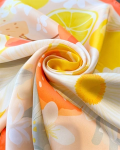 Détail macro d'un foulard en soie montrant l'imprimé floral et citron éclatant
