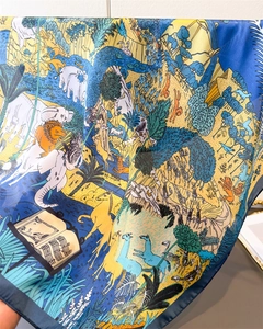 Detailed view of animal print silk scarf featuring lions and tropical flora patterns