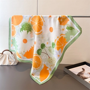 Détail d'un foulard en soie à imprimé citron et fleurs avec des bords verts fins