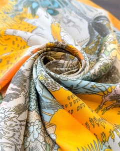 Macro shot of printed silk square scarf showing satin texture and rolled hem details