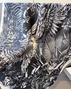 Macro shot of tropical palm leaf and floral prints on silky black and white scarf fabric