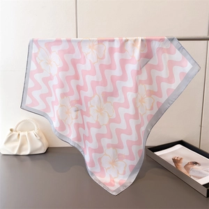 Détail d'un foulard en soie aux motifs de vagues et fleurs d'hibiscus roses et blancs