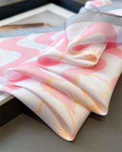 Détail d'un foulard en soie rose avec motifs de vagues abstraites et texture soyeuse