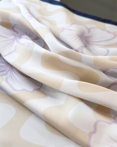 Gros plan d'un foulard en soie aux motifs floraux ondulés et bordures roulées bleues