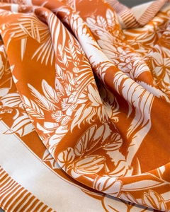 Detailed macro view of vibrant orange tropical floral print on silky satin scarf fabric