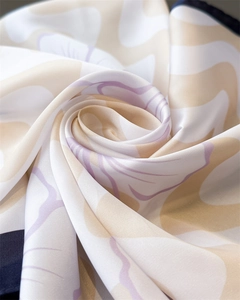 Détail du foulard satiné avec motifs floraux lavande et finitions de l'ourlet roulé