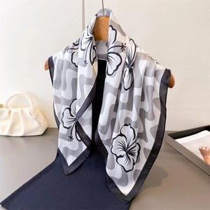 Carré de soie élégant avec imprimé floral noir et motifs ondulés présenté sur un cintre