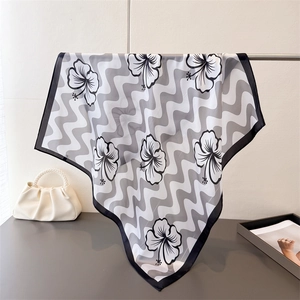 Gros plan d'un foulard en soie avec imprimés d'hibiscus noirs et motifs ondulés élégants