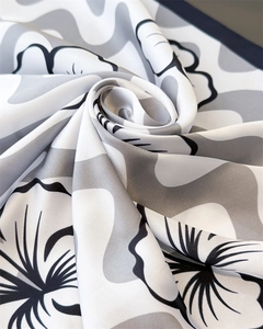 Gros plan d'un foulard en soie à imprimé floral avec texture satinée noire et grise