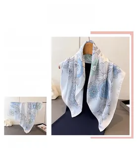 Detail of silk square scarf featuring delicate blue and green floral patterns on white